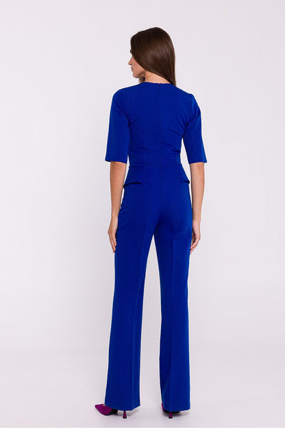 Vrouw draagt Viva Élégance jumpsuit met V-hals en wijde pijpen – chique dames jumpsuit met elegante pasvorm en vrouwelijke uitstraling.